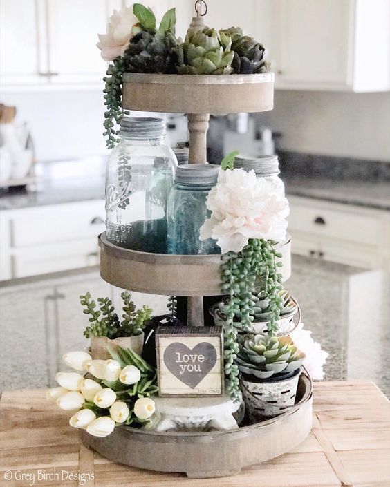 Three-tier tray with artichokes glass jars and floral decor