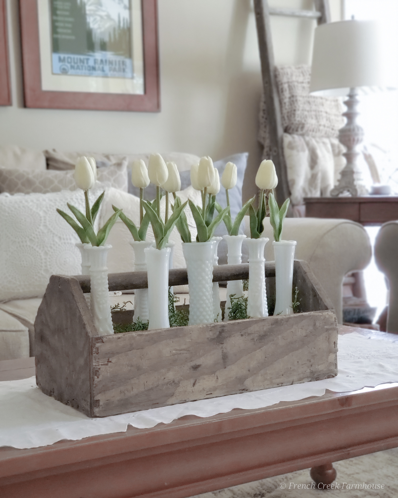 Wood toolbox filled with milk glass vases and white tulips