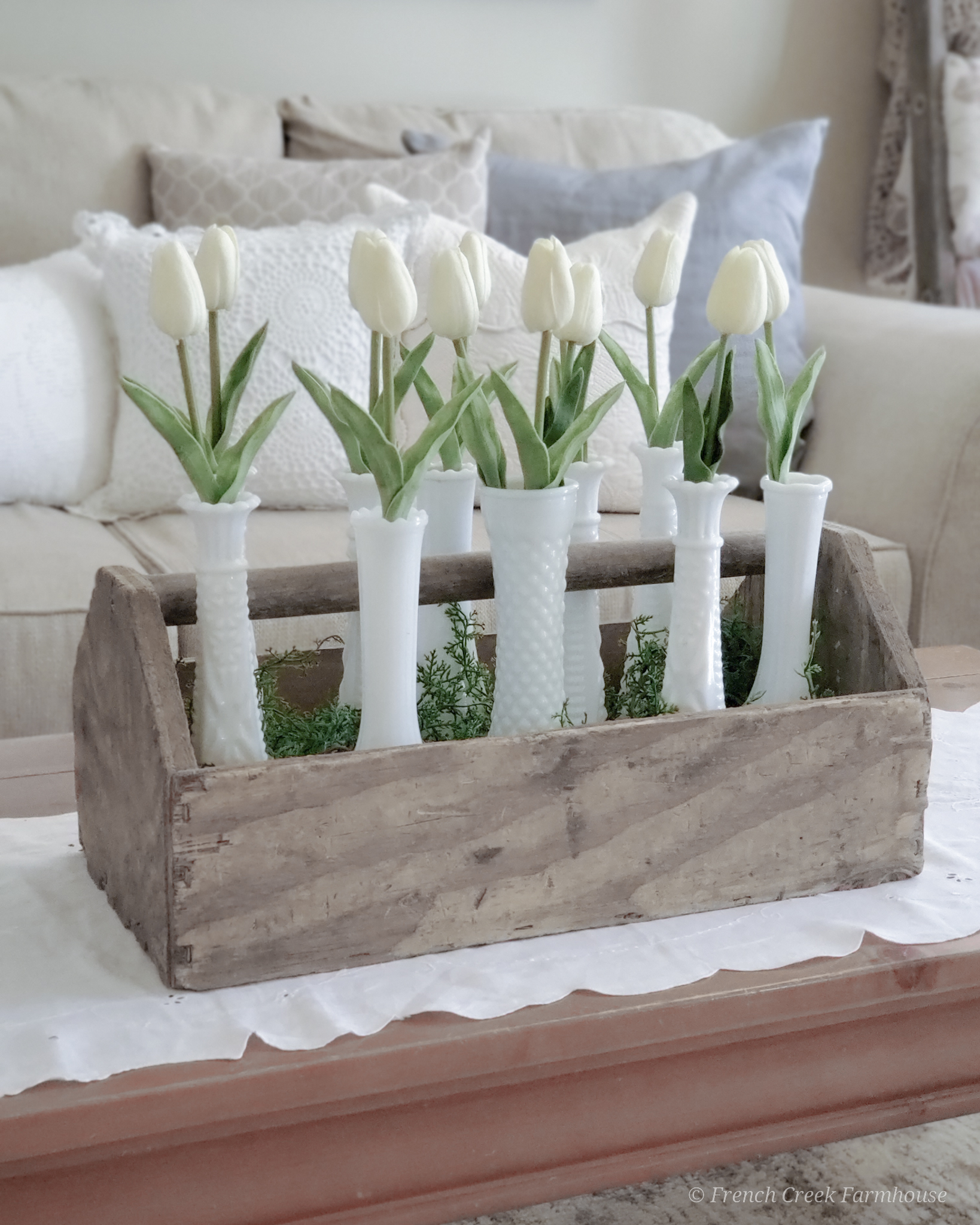 Modern farmhouse spring living room with white tulips and milk glass vases in wood toolbox