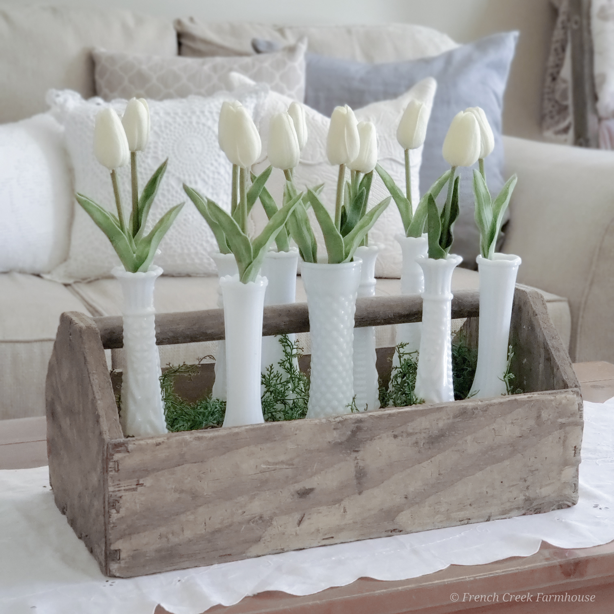 White tulips and milk glass vases in rustic wooden toolbox
