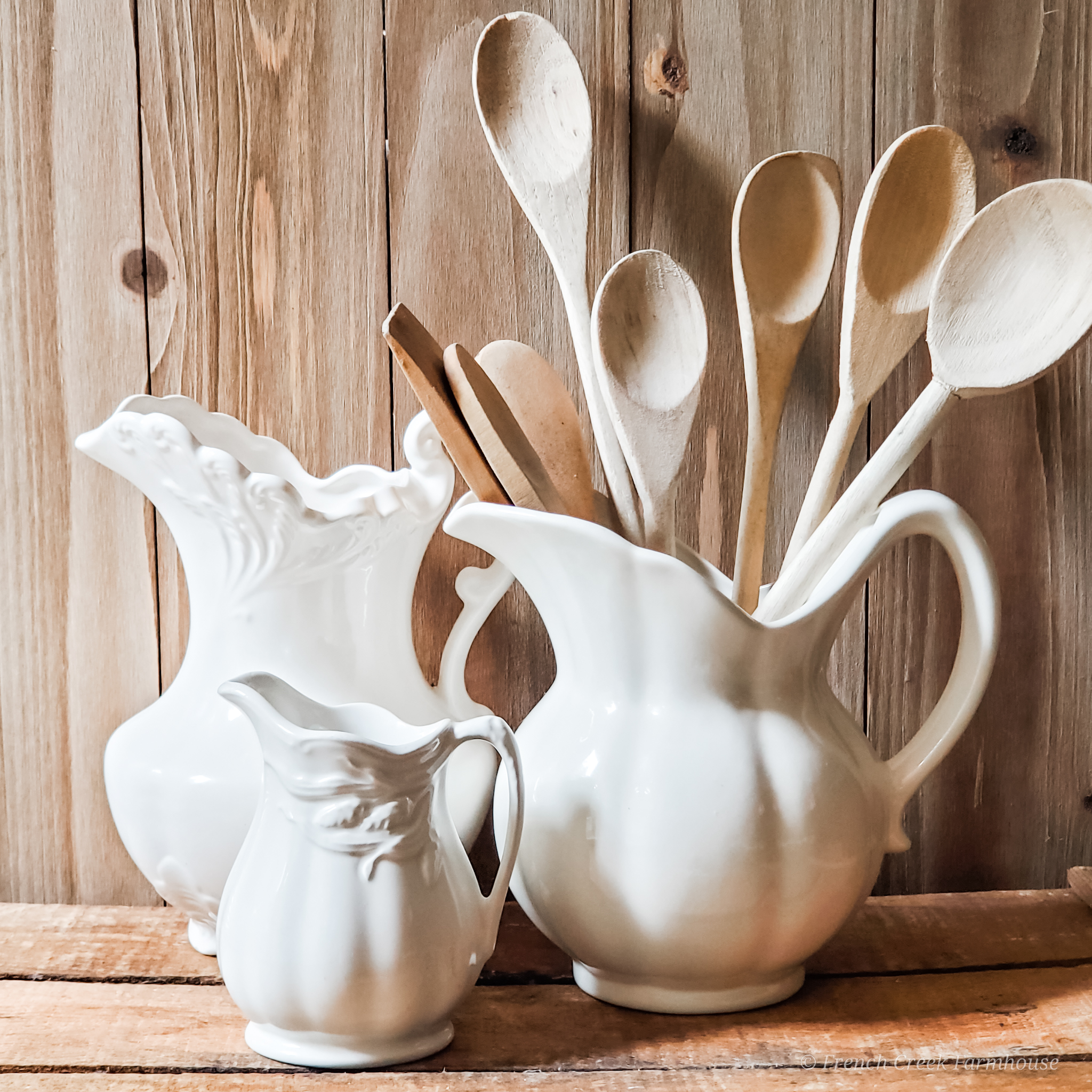 A collection of old wooden spoons in ironstone pitchers make great kitchen decor