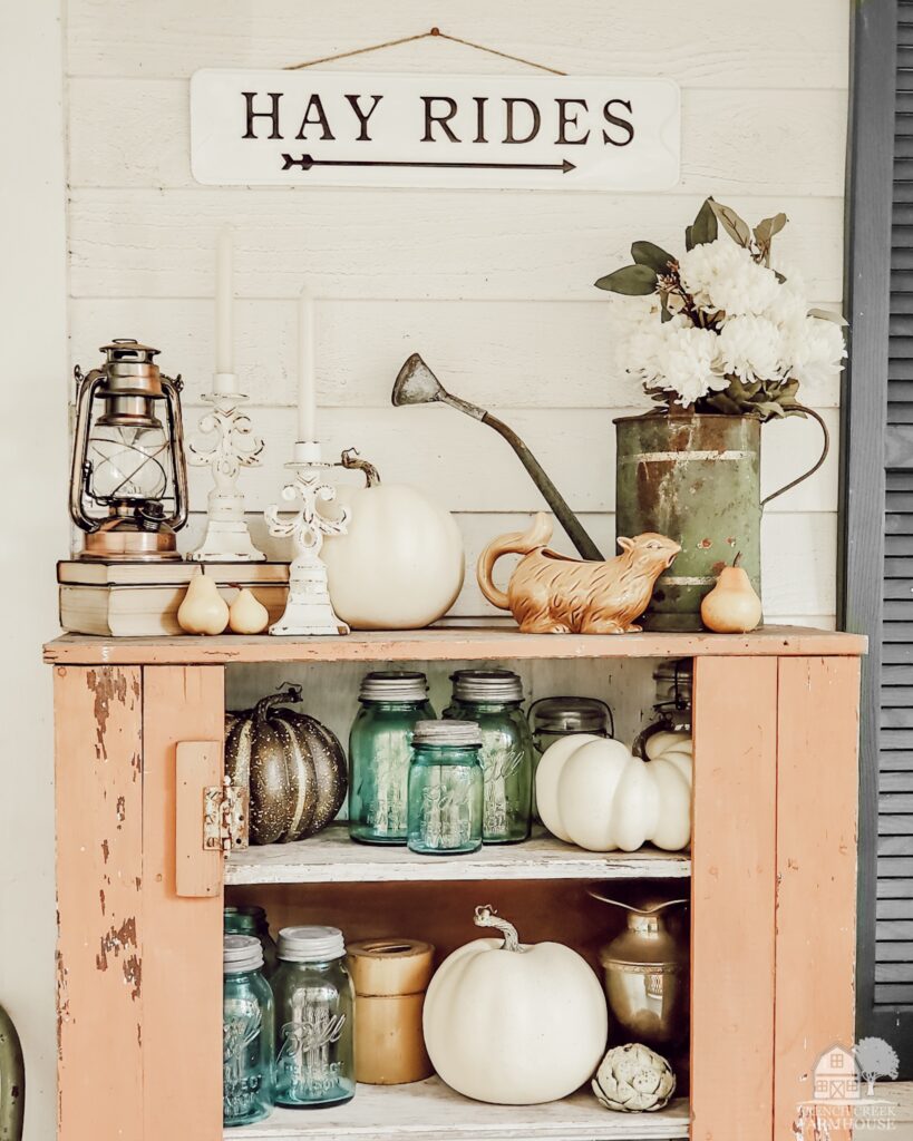 Colorful vintage fall farmhouse decor in a chippy jelly cupboard