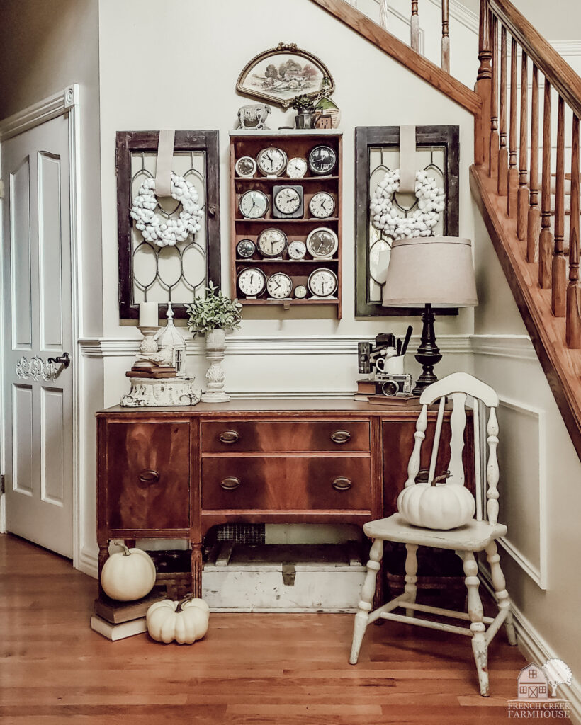 Vintage farmhouse fall foyer with antique buffet and vintage alarm clock collection
