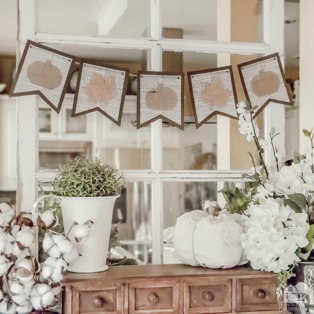 Fall bunting banner strung across a vintage window with neutral autumn home decor