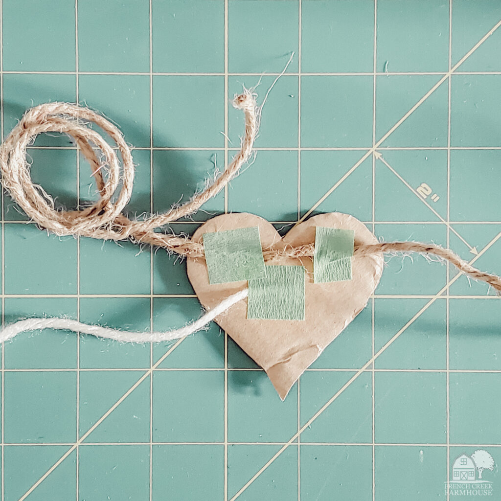 Making yarn wrapped hearts into a garland is easy with just cardboard, yarn, and twine