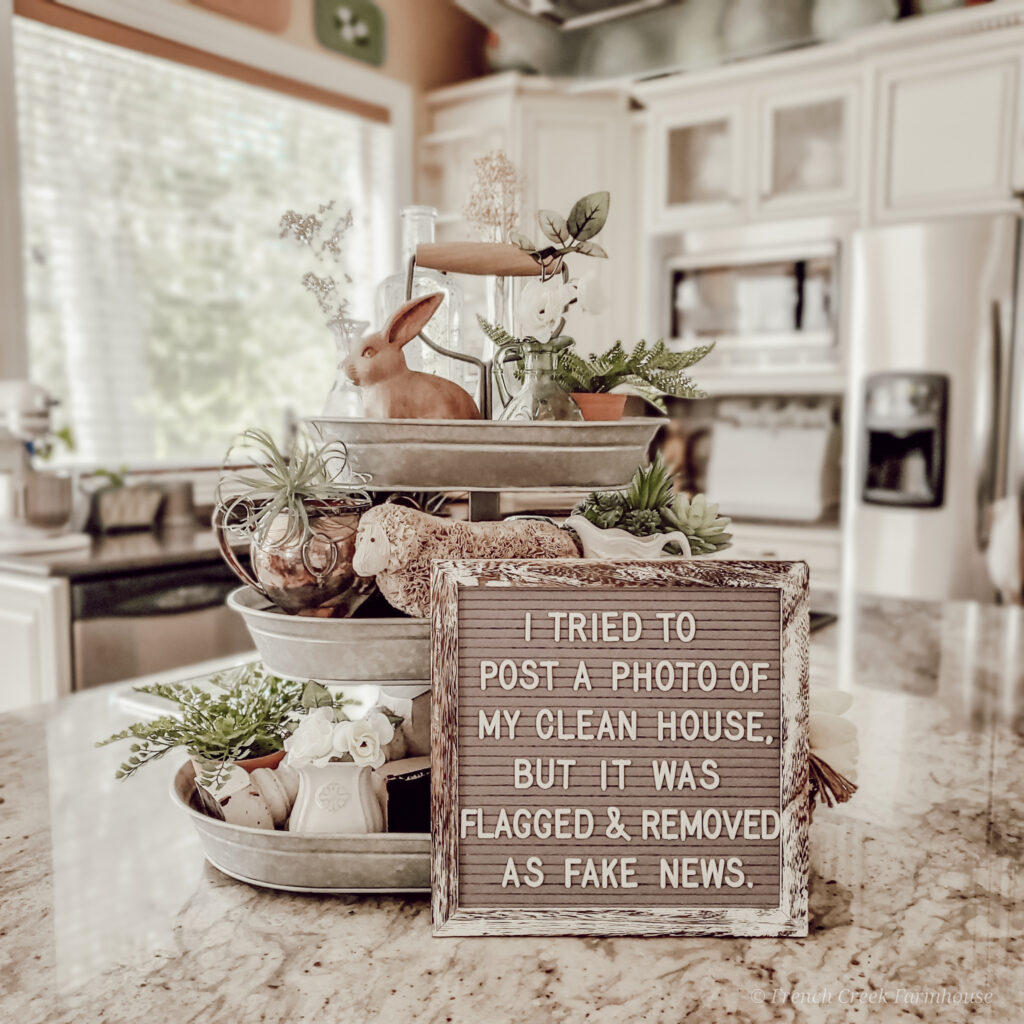 A springtime tiered tray with funny letterboard quote about cleaning house