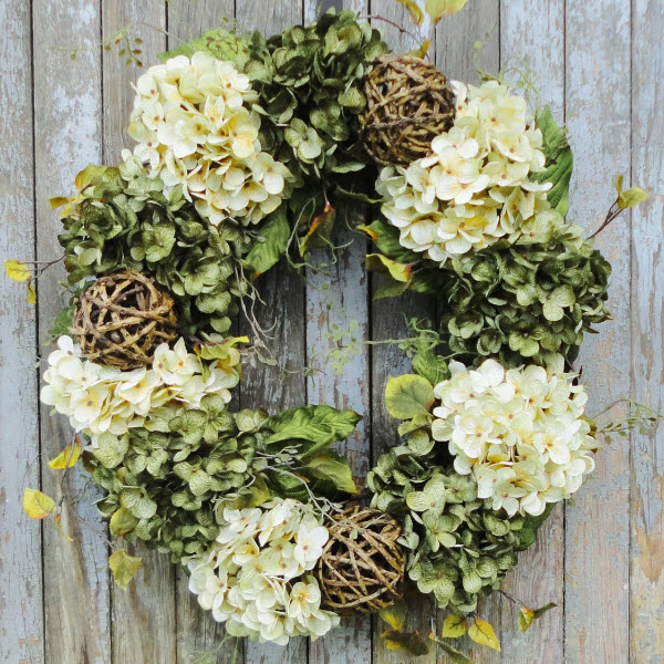 This generously sized wreath is handmade from artificial hydrangea blooms in creamy white and decadent green.